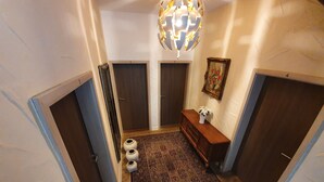 A hallway with wooden flooring, a patterned rug, a wooden bench, and a decorative light fixture. - Osteria Del Vino Cochem (Cochem)