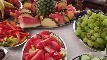 A table with various fruits and vegetables including watermelon, pineapple, grapes, cucumbers, and tomatoes.