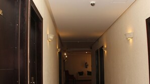 A hotel hallway with a patterned carpet, wall-mounted lights, and a door on the left. - Jeddah Palace Hotel (Amman)