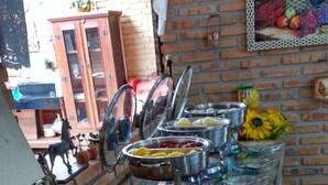 Buffet com diversos alimentos e parede de tijolos ao fundo.