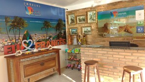 Recepção com decoração praiana, um mural, balcão de madeira e exposição de lembranças.
