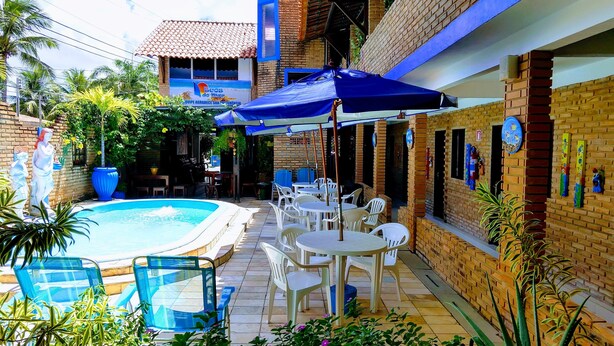 Uma área na beira da piscina com piscina, mobiliário de exterior e um alpendre coberto.