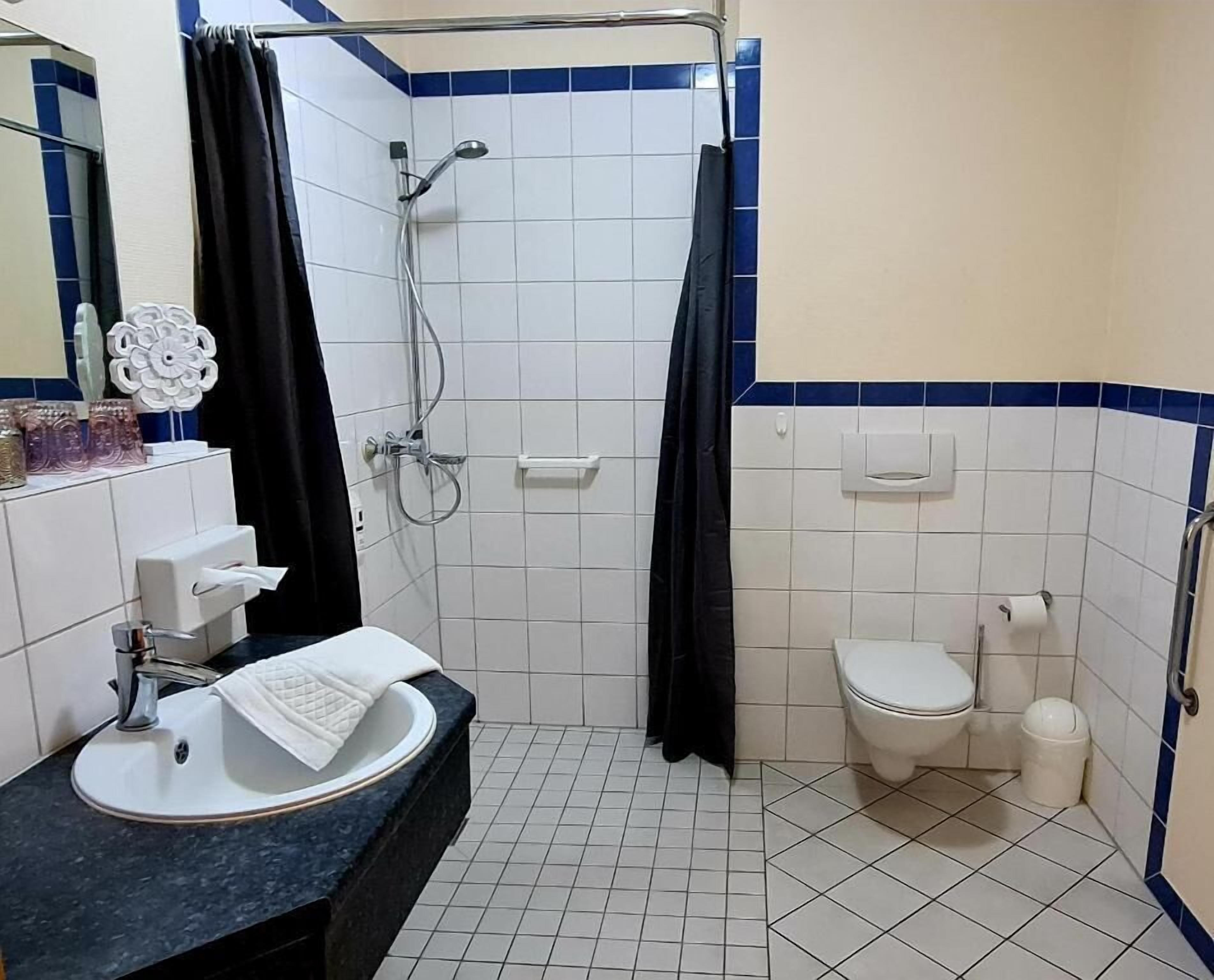 A bathroom with a shower, toilet, sink, and mirror.