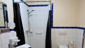 A bathroom with a shower, toilet, sink, and mirror.