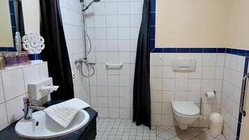A bathroom with a shower, toilet, sink, and mirror.