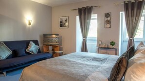 A bedroom with a bed, a sofa, a TV, and a small table with decorative items.