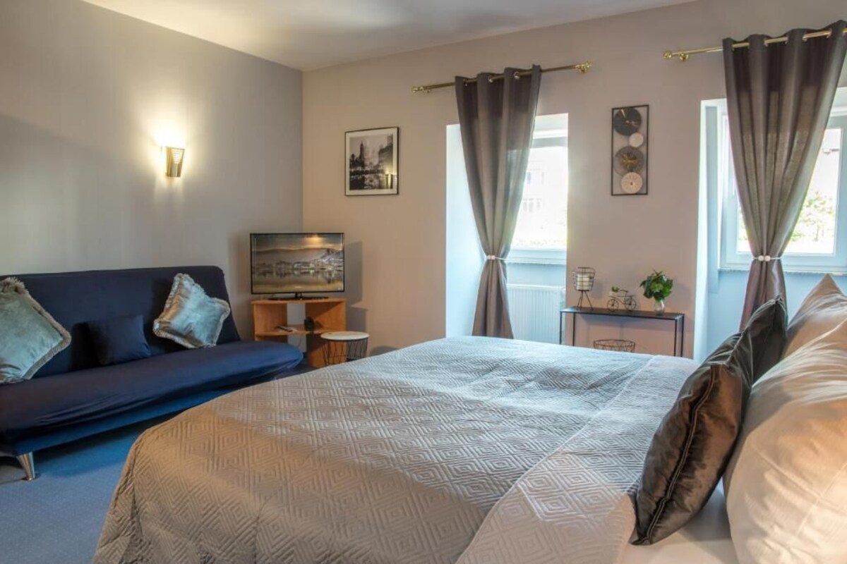Een slaapkamer met een bed, een bank, een televisie en een klein tafeltje met decoratieve objecten.