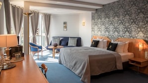 A hotel room with a bed, a desk, a chair, a small table, and a sofa.