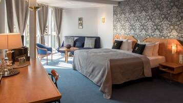 A hotel room with a bed, a desk, a chair, a small table, and a sofa.