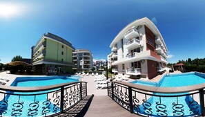 Un hôtel doté de deux piscines, d’une terrasse en bois et surplombant un ciel d’un bleu limpide.