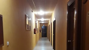 Un pasillo largo y estrecho con paredes amarillas y suelo de baldosas.