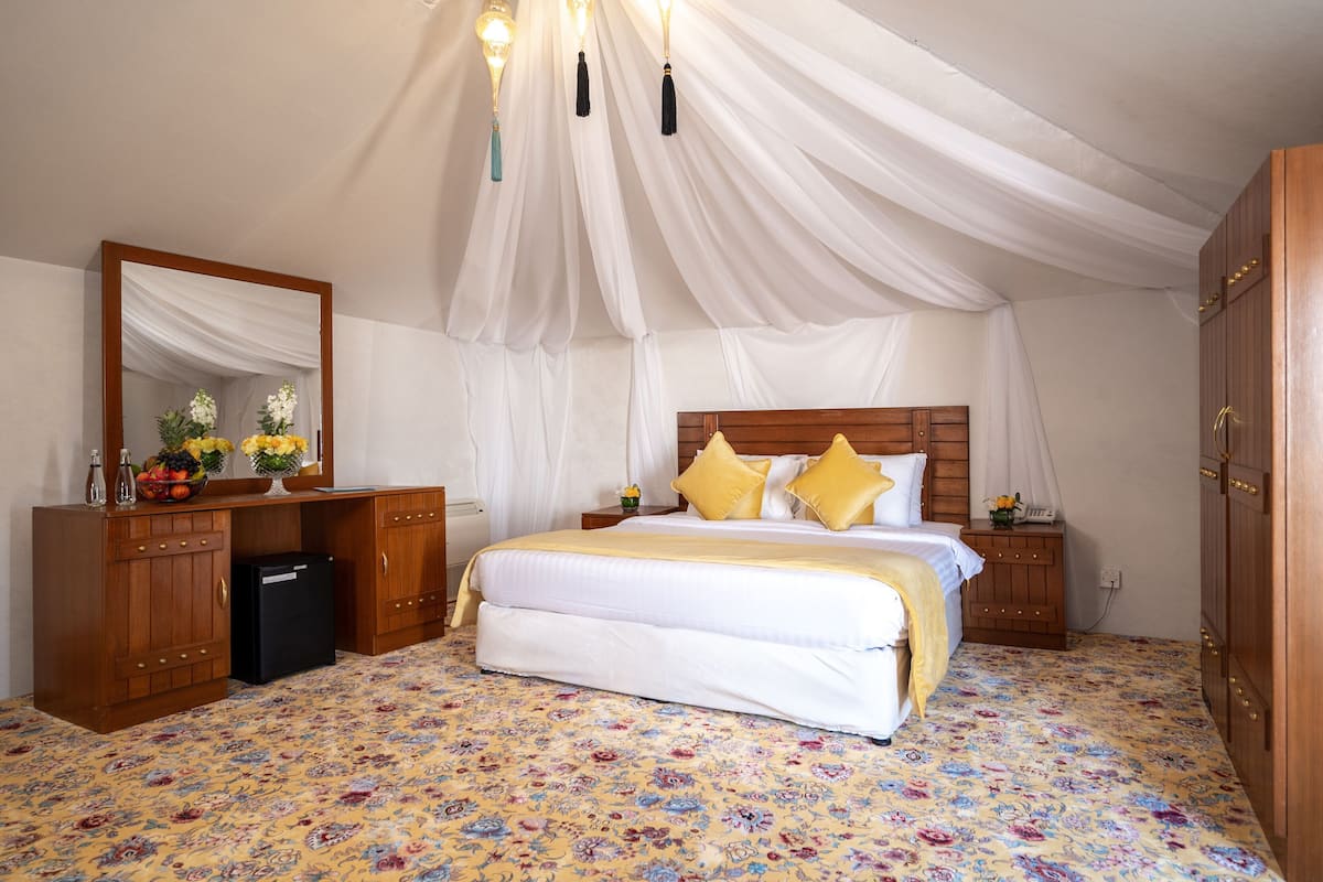 A bedroom with a bed, a dresser, a mirror, and a nightstand.