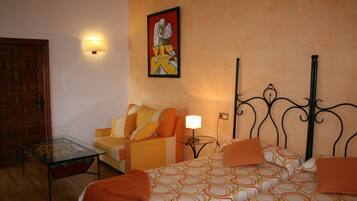 Una habitación de hotel con una cama, un sofá, una mesa de vidrio y una lámpara de pared.
