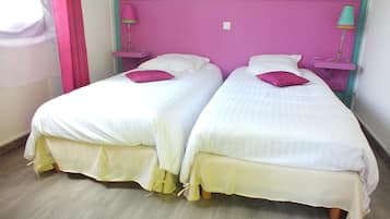 Two single beds with white linens and pink headboards in a room with teal walls.