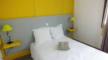 Una habitación de hotel con una cama, dos mesitas de noche y una mesilla.