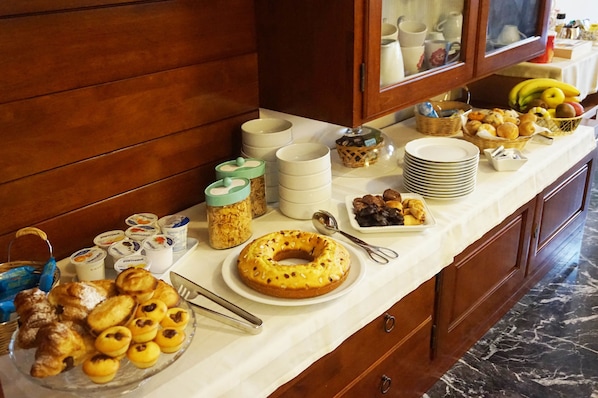 A buffet table with various food items, including pastries, fruits, and condiments. - B&B Piazza 300mila (Lecce)