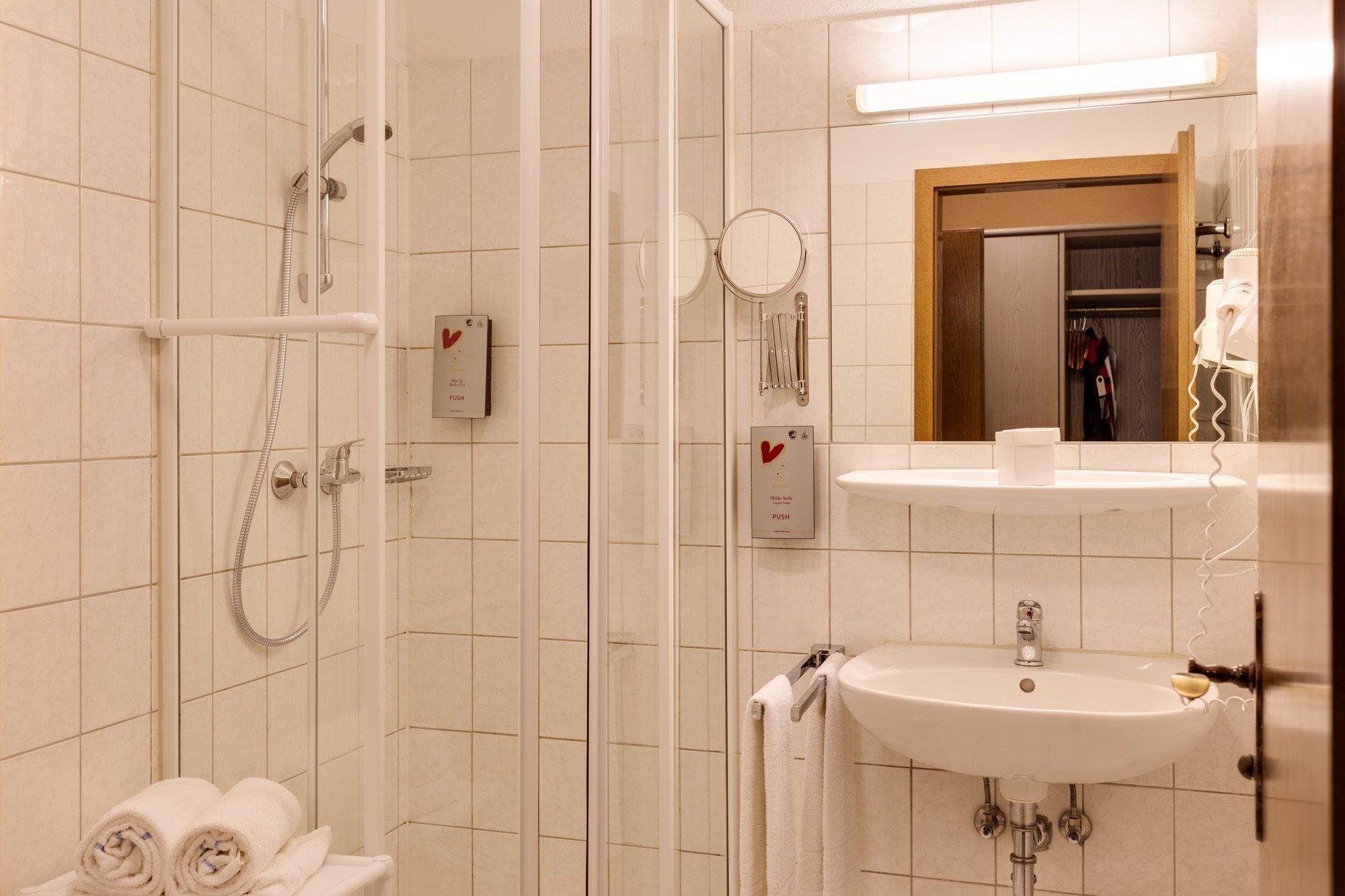Un baño con ducha, lavamanos y espejo.