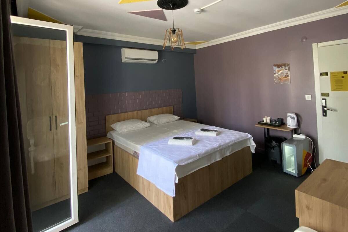 Een kamer met een bed, een kledingkast, een bureau en een plafondventilator.