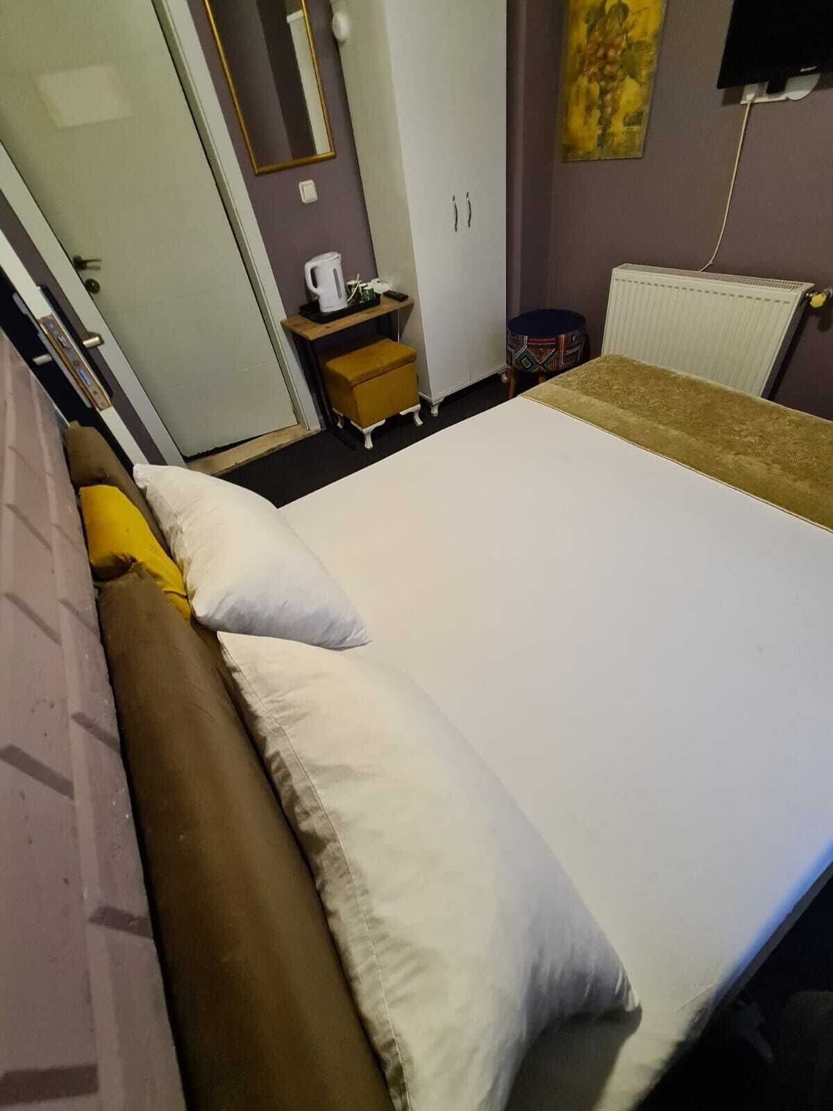 Ein Hotelzimmer mit einem Bett, einem kleinen Tisch mit Wasserkocher, einer Heizung und einem Fernseher an der Wand.