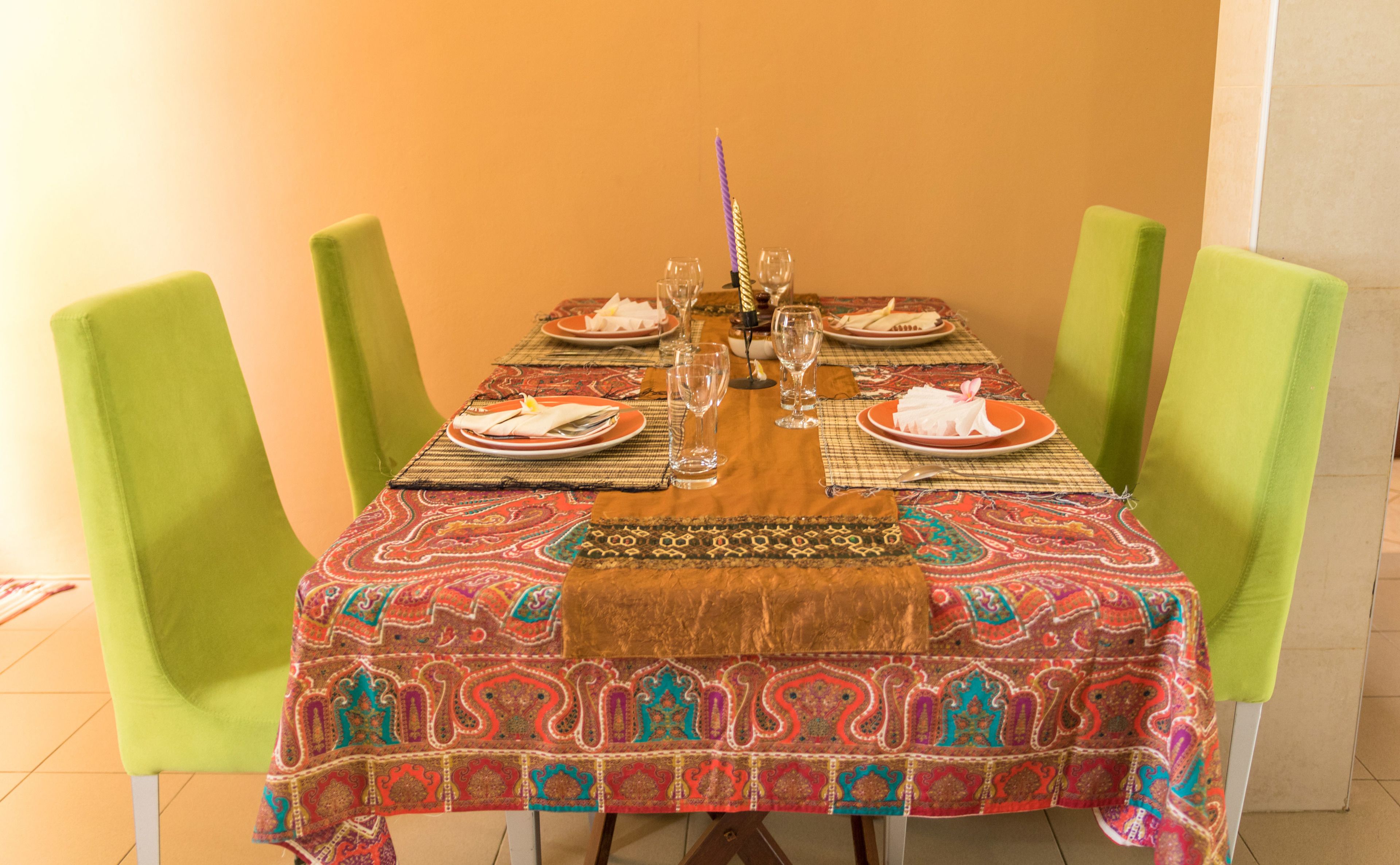 Een gedekte eettafel met borden, glazen en een kaars.