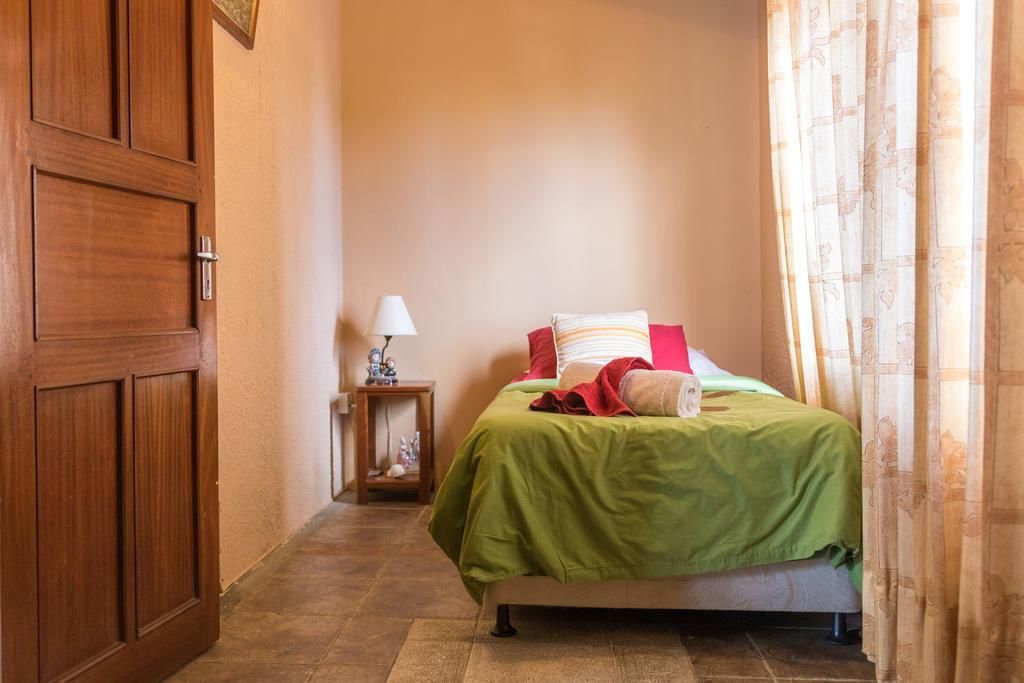 Un dormitorio con cama, mesita de noche, lámpara y puerta.