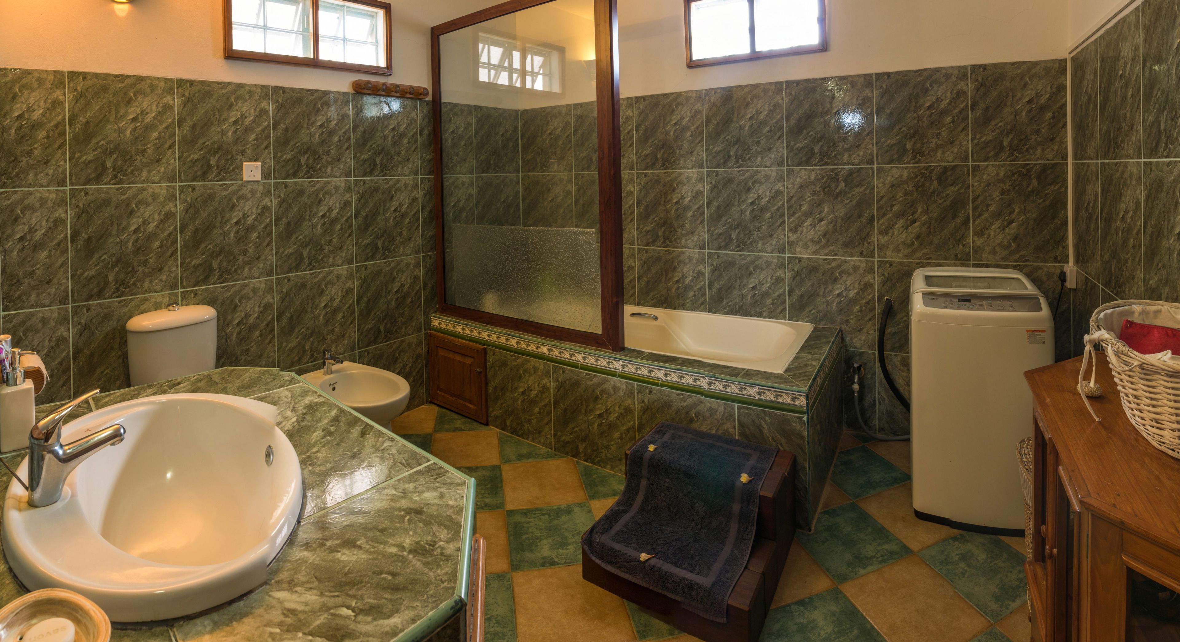 Een badkamer met wastafel, toilet, spiegel en een bad.