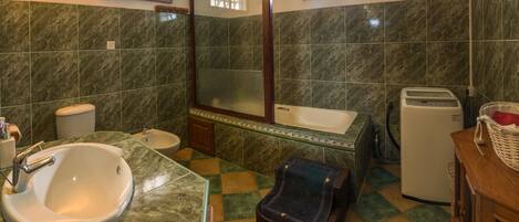 A bathroom with a sink, toilet, mirror, and a bathtub.
