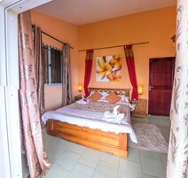 Un dormitorio con una cama de madera, cortinas rojas, un cuadro en la pared y una puerta roja.
