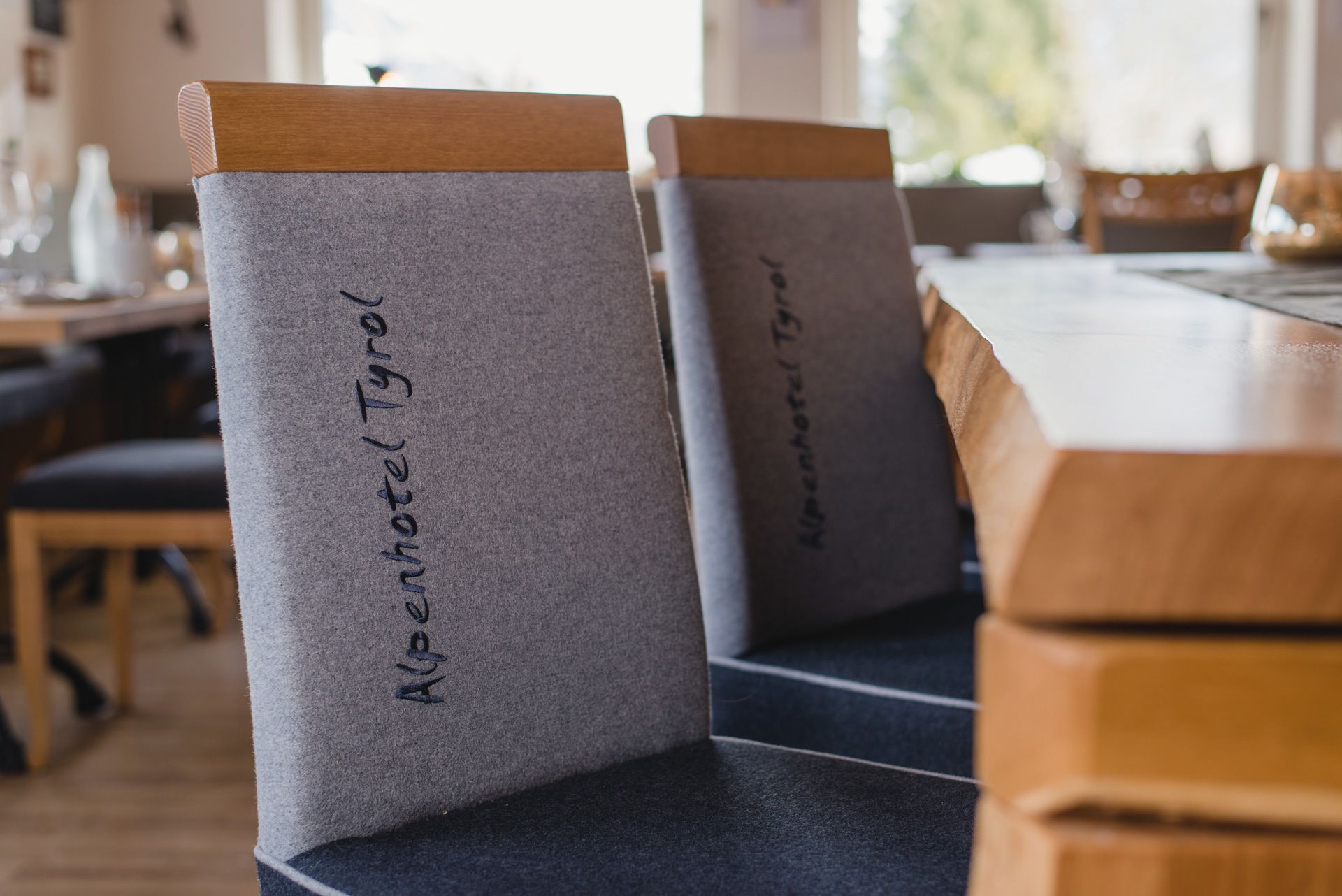 A row of chairs with grey cushions and wooden tops, labeled "Alpenhotel Tyrol".