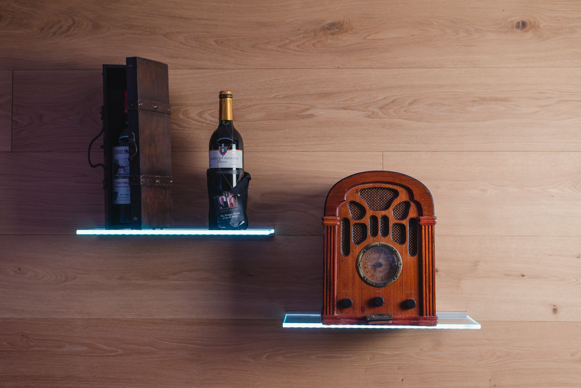 Eine Holzwand mit zwei Regalen, eines mit einer Weinflasche und das andere mit einem Vintage-Radio.