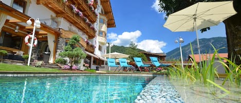 Una piscina al aire libre, una piscina natural, sombrillas, tumbonas