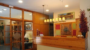 Un espace d’accueil avec un comptoir en bois, une porte en verre et une lampe fixée au mur.