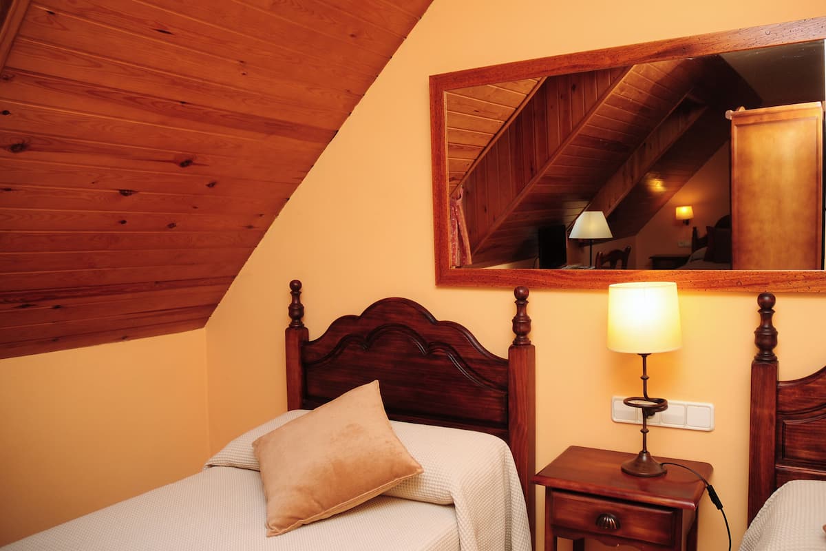 Ein Schlafzimmer mit Holzboden, einem Bett mit Kopfteil, einem Nachttisch mit Lampe und einem Spiegel an der Wand.