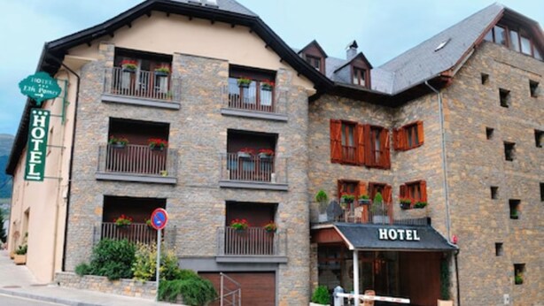 Un hôtel à la façade en pierre, doté de nombreux balcons ornés de jardinières et d’une enseigne indiquant qu’il s’agit d’un hôtel.