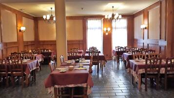 A banquet hall with multiple tables and chairs, arranged in rows.