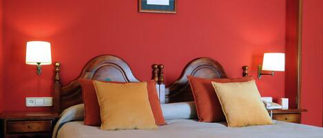 A hotel room with a large bed, two bedside tables, a nightstand, and a framed picture on the wall.