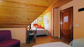 A room with a sloped ceiling, wooden walls, a bed, a desk with a chair, and a door with a notice on it.