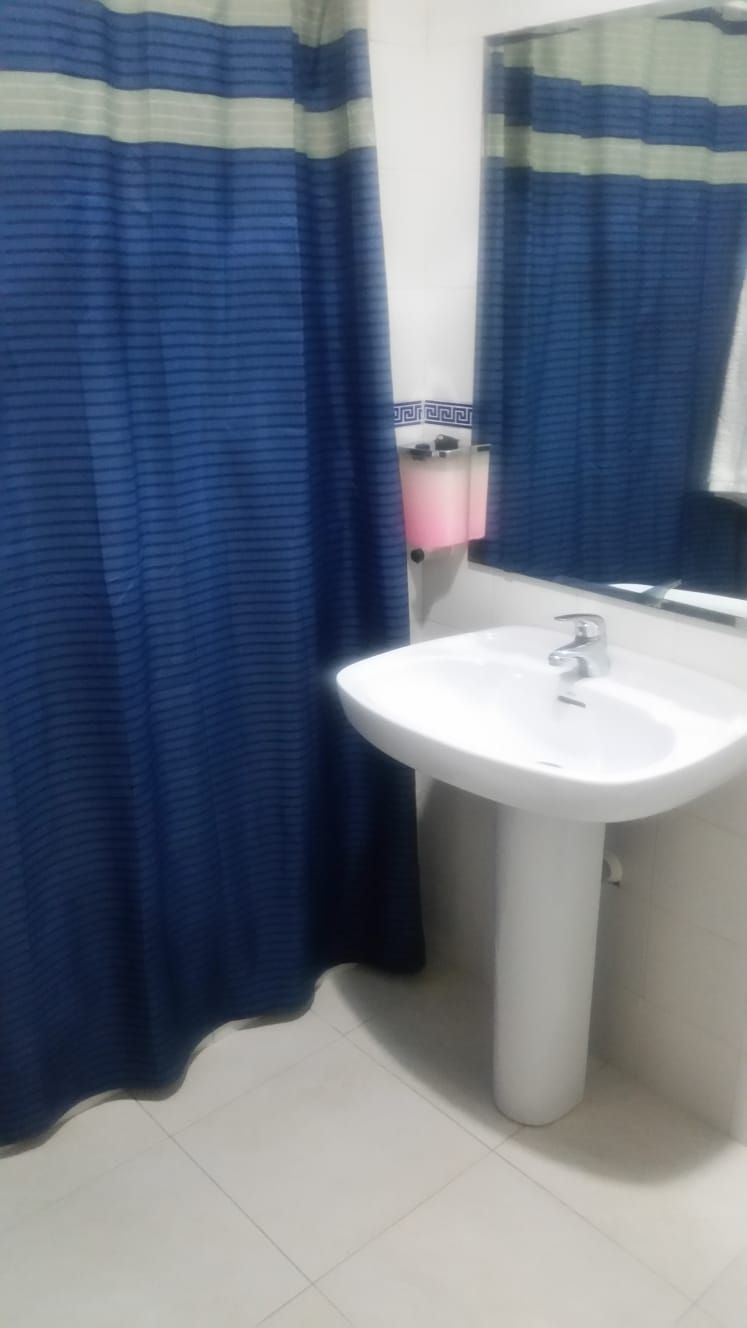 A bathroom with a white sink, a mirror above it, and a blue striped shower curtain.