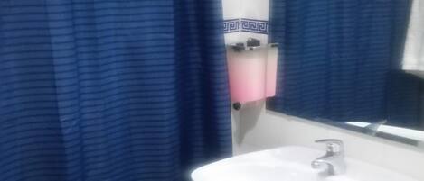 A bathroom with a white sink, a mirror above it, and a blue striped shower curtain.