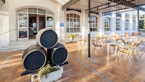 Un espacio al aire libre techado con un patio, mesas, sillas y barriles apilados.