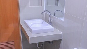 A bathroom with a white sink, mirror, and toilet. - Butuan Grand Palace Hotel Annex (Butuan)