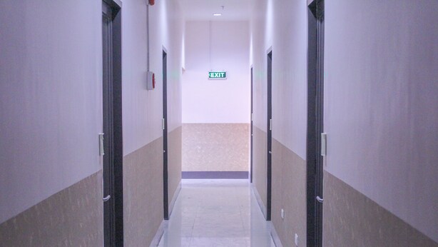 A long, narrow hallway with a beige and white color scheme, leading to an exit sign at the end. - Butuan Grand Palace Hotel Annex (Butuan)