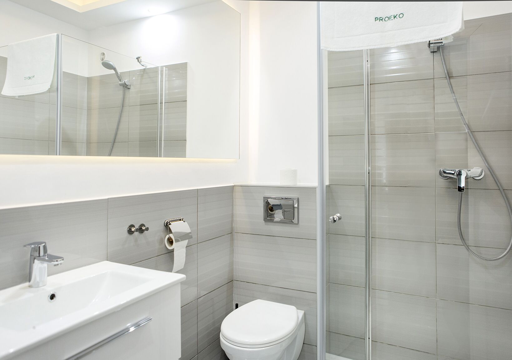 A modern bathroom with a glass shower enclosure, a white sink, and a toilet.