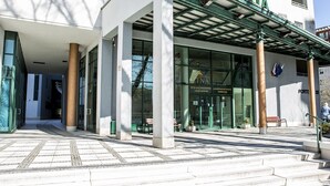 A building with a modern entrance featuring large glass doors and a green awning.