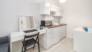A compact kitchen with white cabinets, a microwave, a coffee maker, and a small sink.