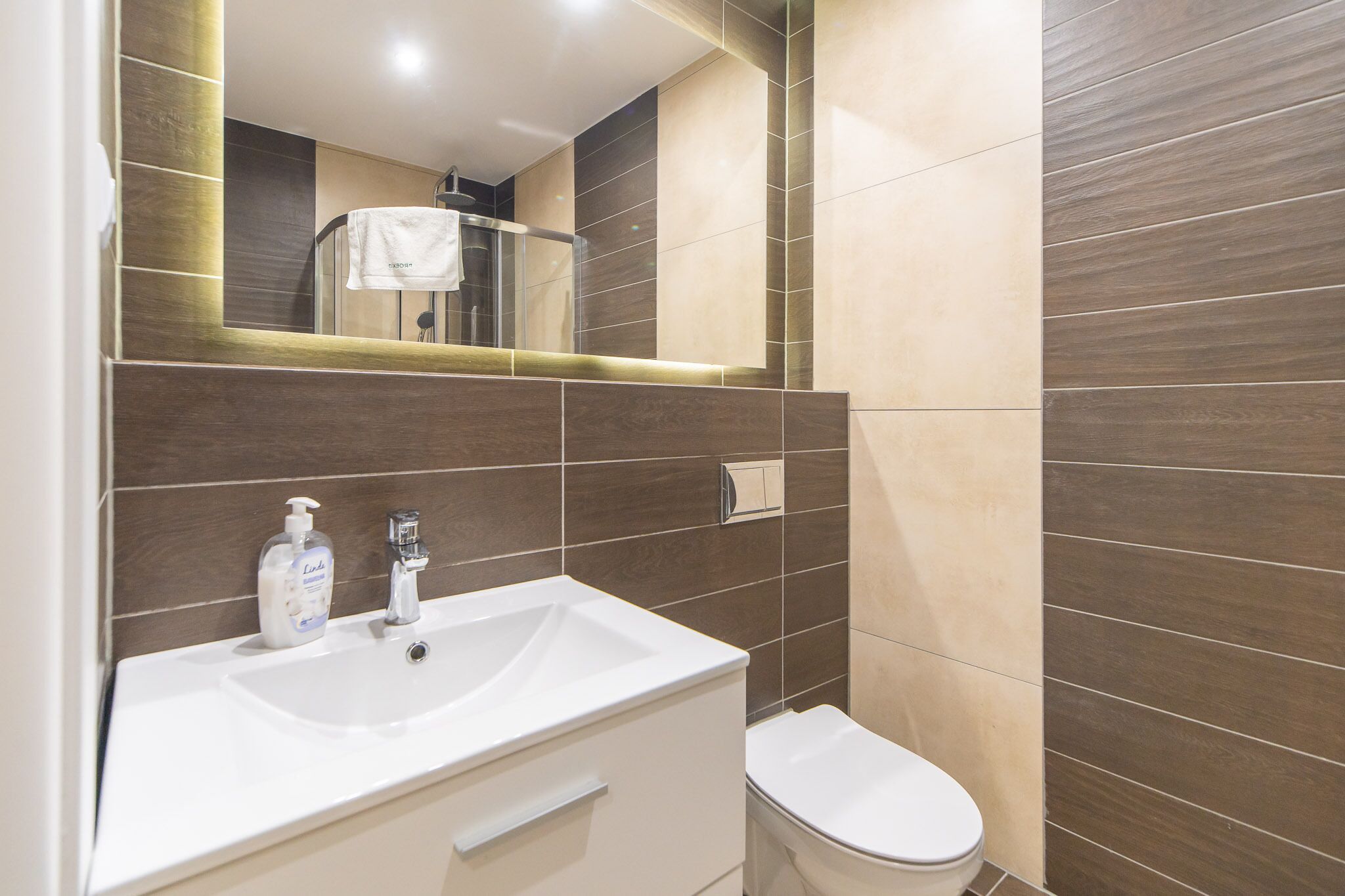 A modern bathroom with a white sink, a mirror, and a toilet.