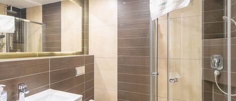 A modern bathroom with a glass shower enclosure, a white sink, and a toilet.