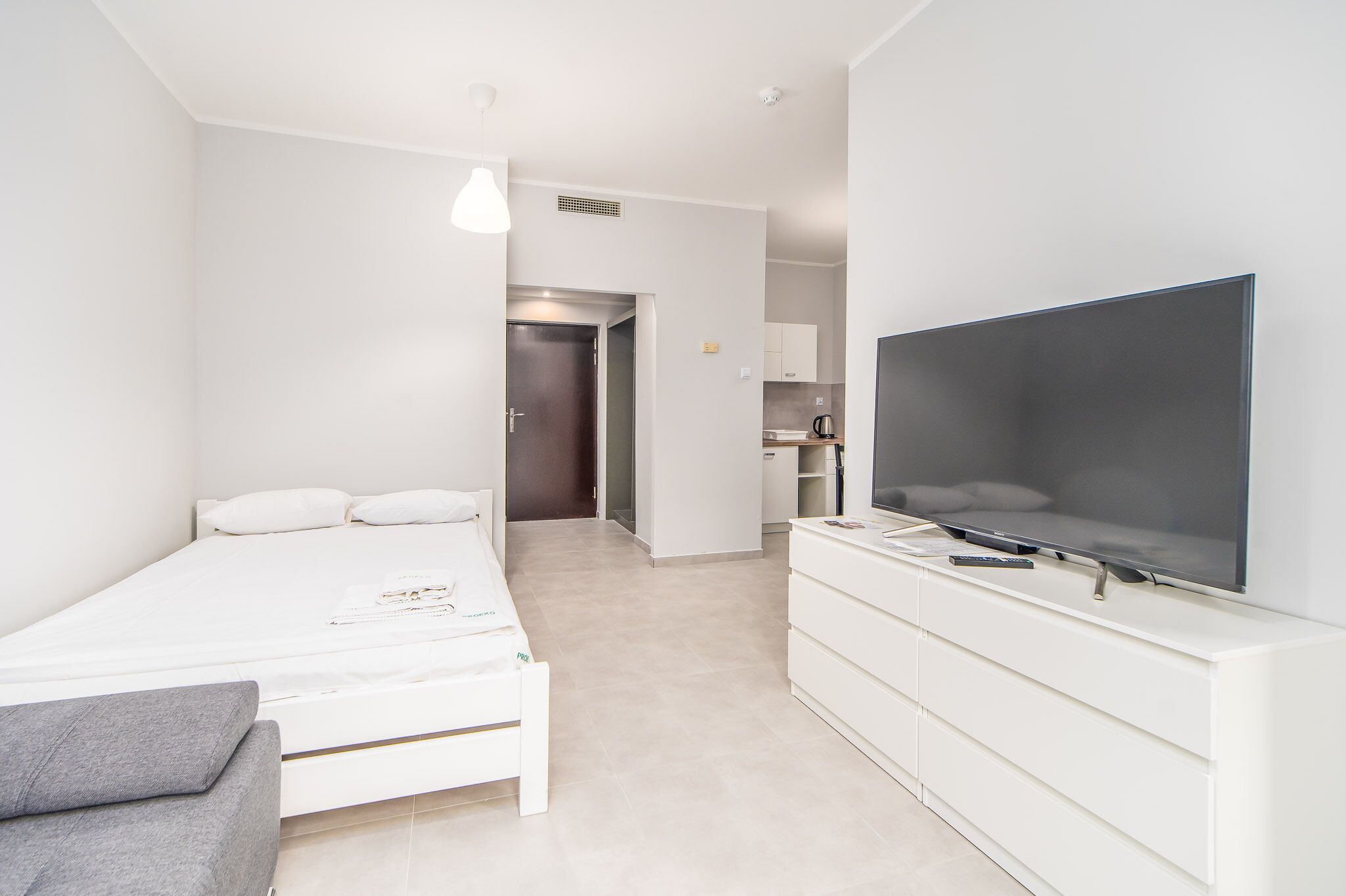 Een moderne slaapkamer met een bed, een televisie en een dressoir.