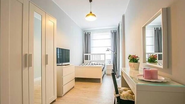 A modern bedroom with a bed, a TV, a desk, and a wardrobe.