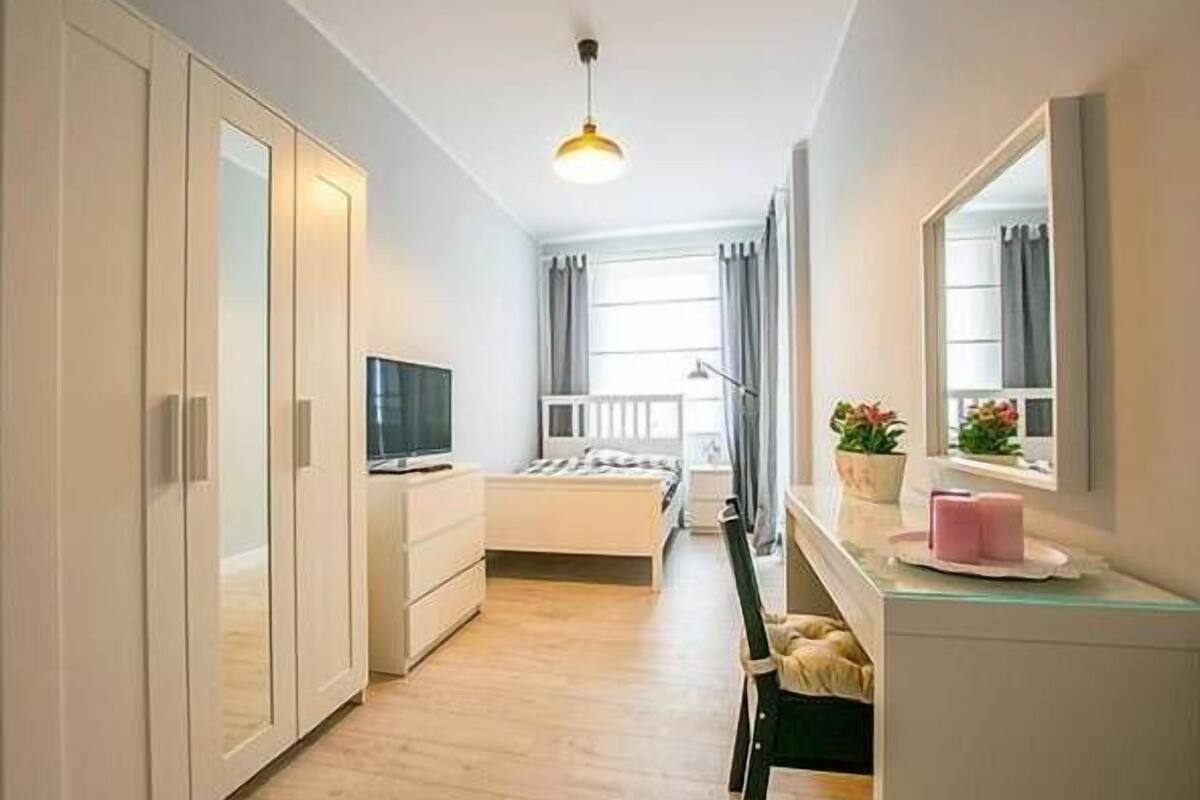 Ein modernes Schlafzimmer mit einem Bett, einem Fernseher, einem Schreibtisch und einem Kleiderschrank.
